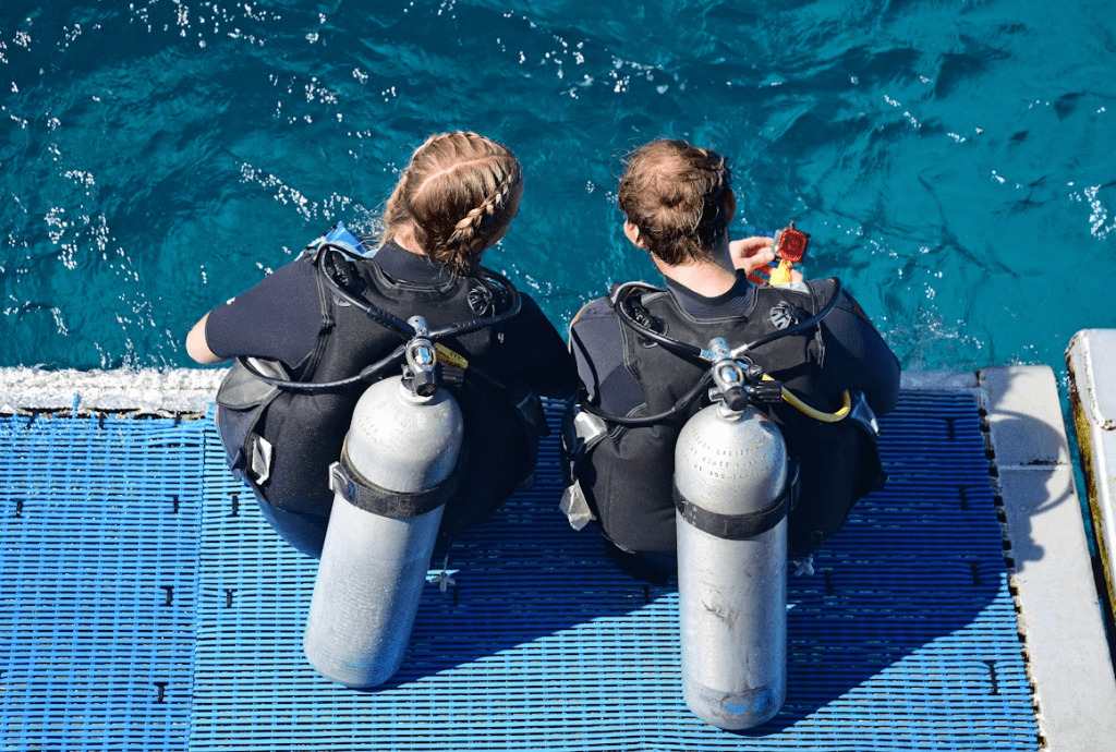 Dive Buddies. A couple of divers complete their safety checks before scuba diving the Outer Great Barrier Reef.